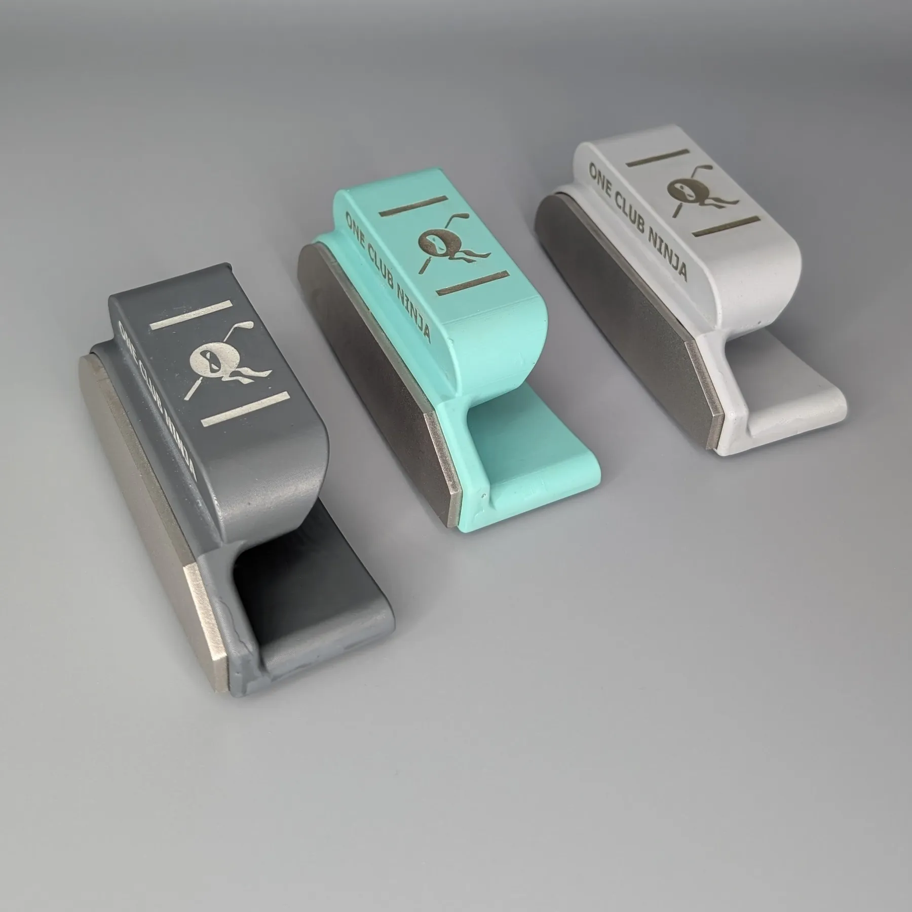 The One Club Ninja putter attachment in Obsidian, Green and Light Gray on a studio backdrop